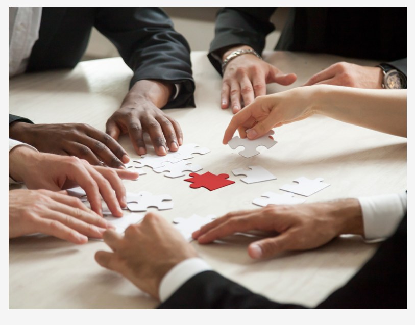 Manos armando un rompecabezas, pieza roja al centro